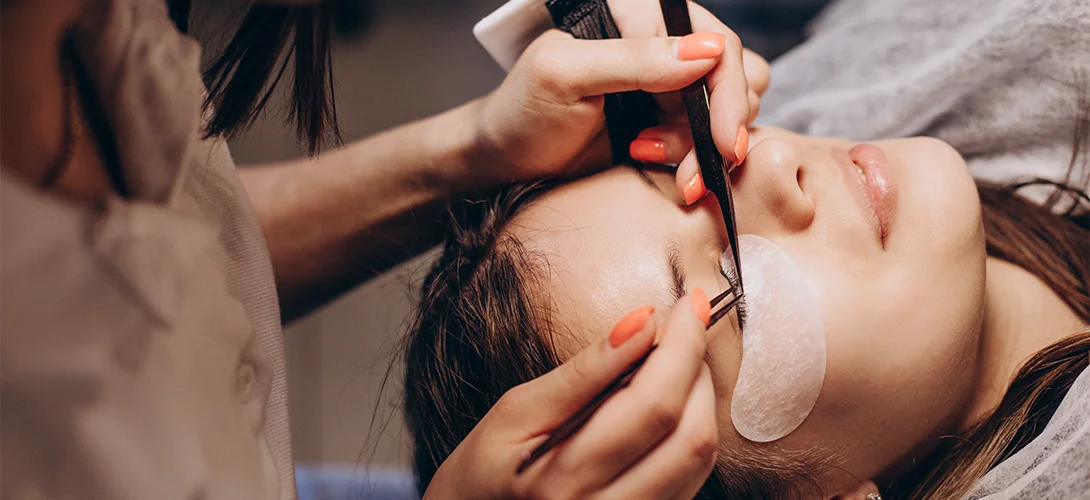 Lash technician working on a reclining client with under-eye gel pads in place